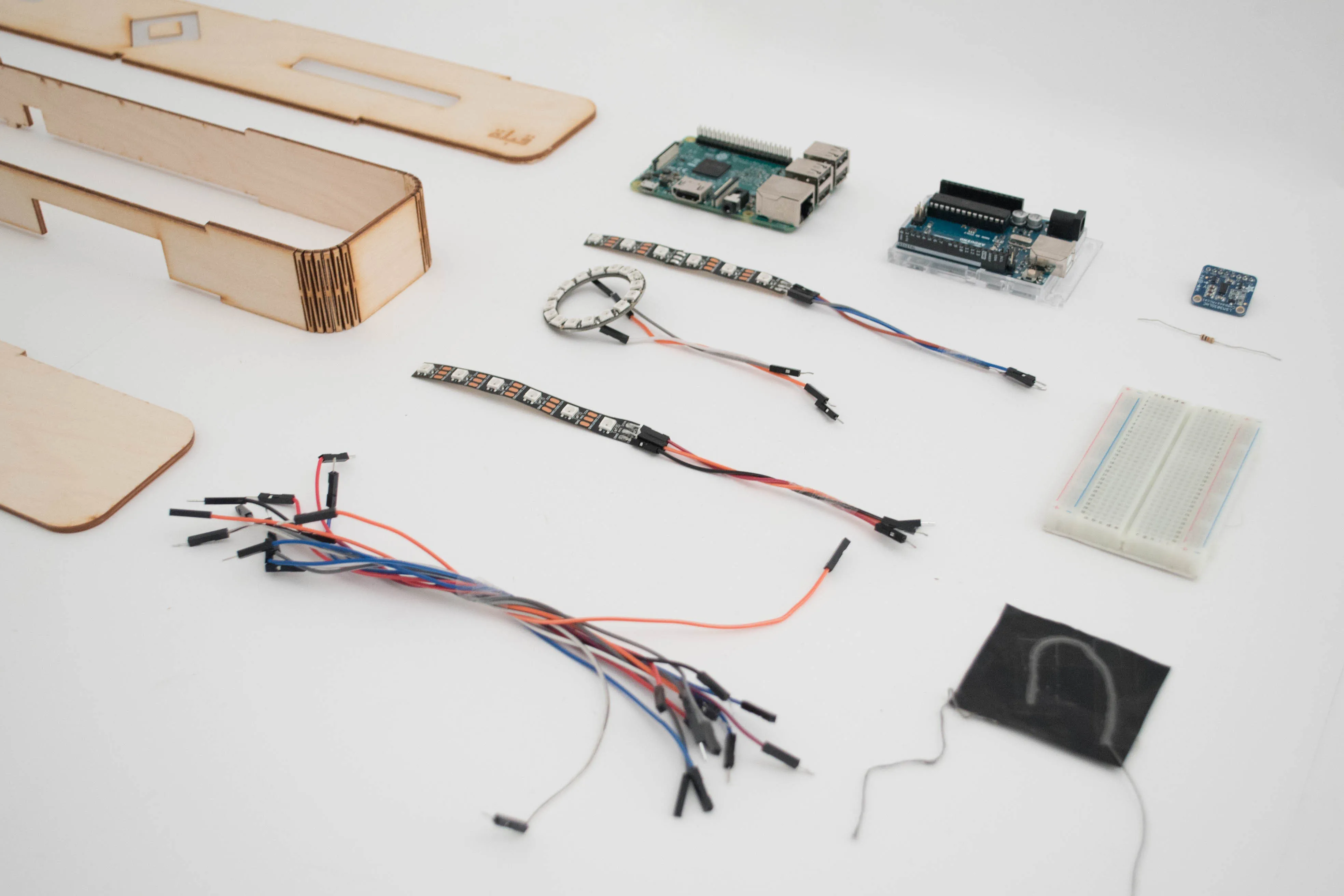 Components: laser-cut wood enclosure, Raspberry Pi, Arduino, NeoPixel LED strips, magnetometer, jumper wires, breadboard.